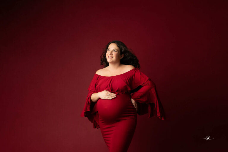 séance maternité dans le studio de Sabrina Esteves à Gaillon.
Femme enceinte habillé d'une robe rouge sur fond rouge.